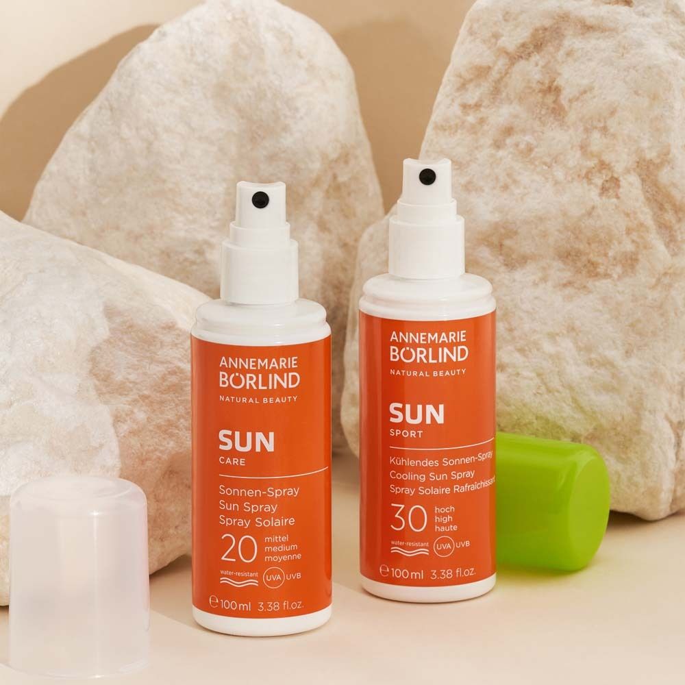 Deux flacons ANNEMARIE BÖRLIND Sun Spray. Flacons orange avec bouchon blanc. Texte : SUN CARE, 20, 30.