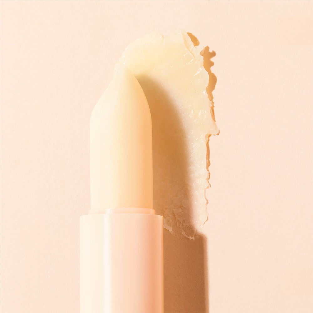 Lippenbalsem, crèmekleurig, uit de huls gedraaid. Op crèmekleurige achtergrond.