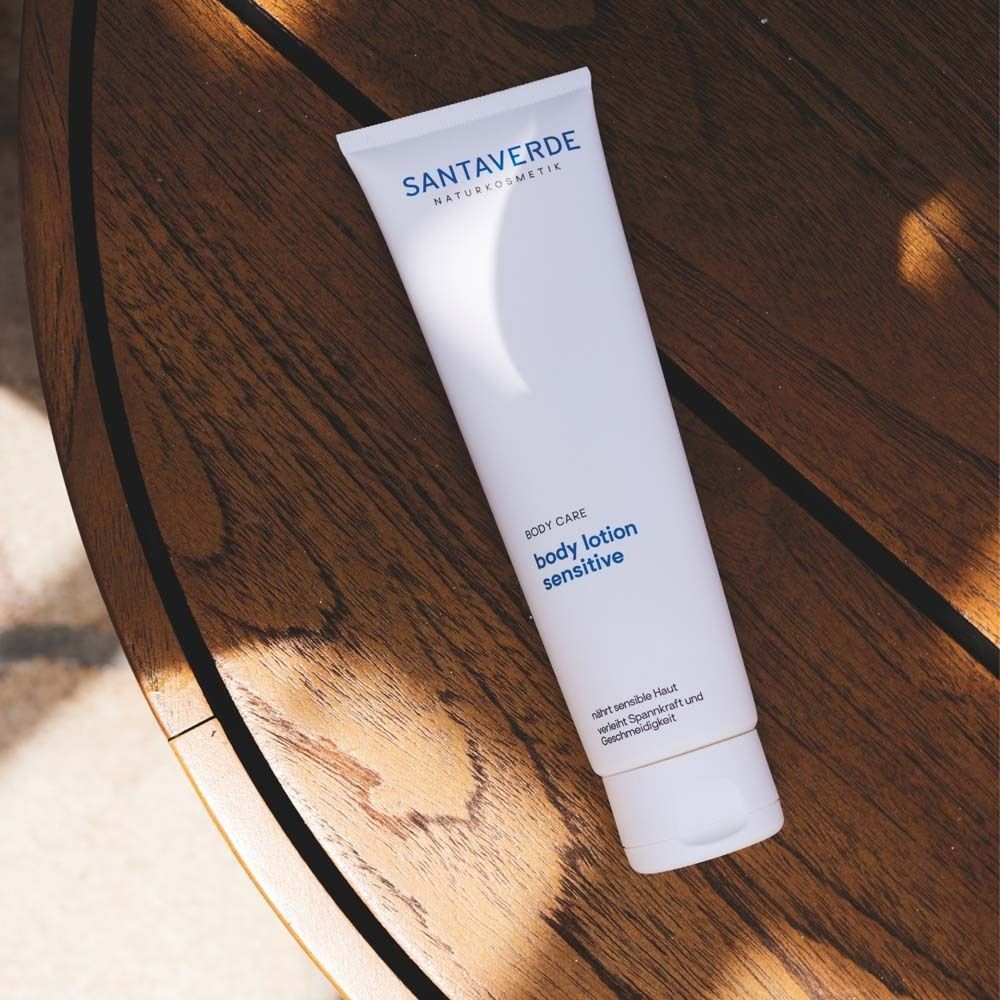 Witte tube SANTAVERDE body lotion sensitive op houten oppervlak. Product voor de gevoelige huid.