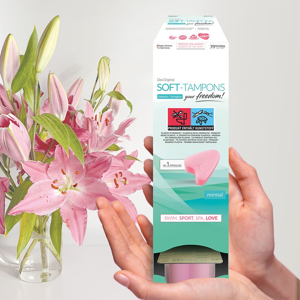 Personne tenant un emballage de tampons roses. Texte: Das Original SOFT-TAMPONS, normal. Pour nager, faire du sport, spa, amour.
