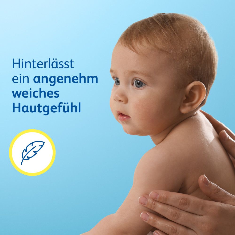 Bébé avec des mains qui l'enduisent de crème. Texte : Laisse une sensation de peau agréablement douce. Symbole de plume.