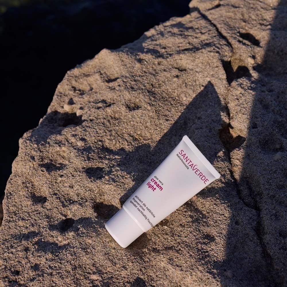 Witte tube "cream light" op steen. SANTAVERDE-logo zichtbaar. Product voor gezichtsverzorging. Schuine perspectief.