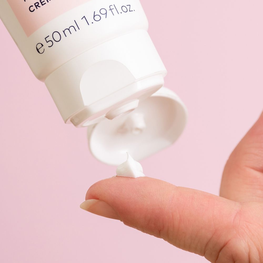 Produit crème blanc pressé d'un tube sur un doigt.