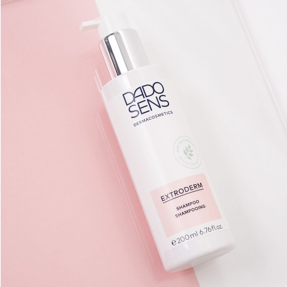 DADO SENS EXTRODERM Shampoo. Flacon avec pompe, étiquette rose. Sur fond rose et blanc.