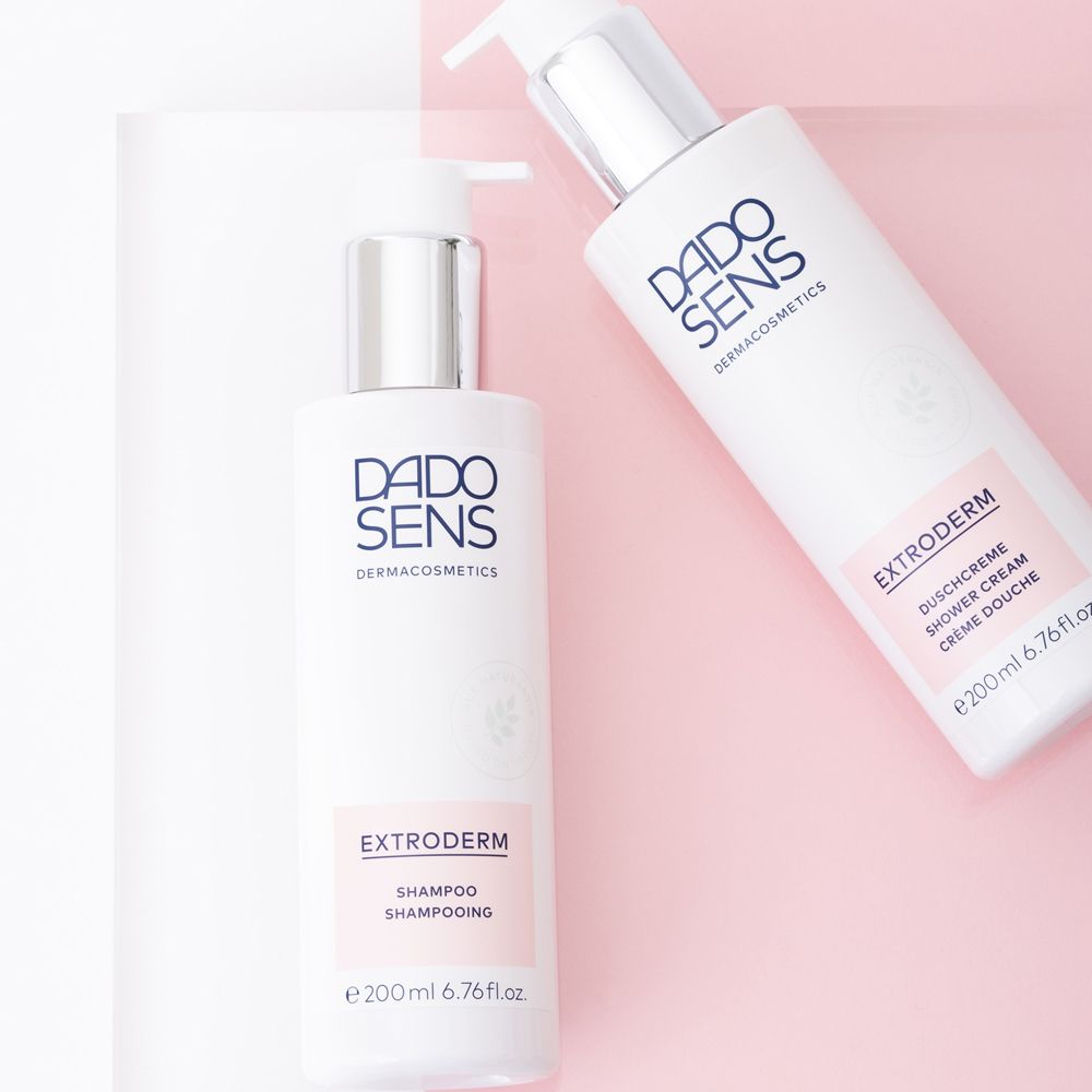 Deux flacons de DADO SENS EXTRODERM Shampoo. Étiquettes roses. Sur fond rose.