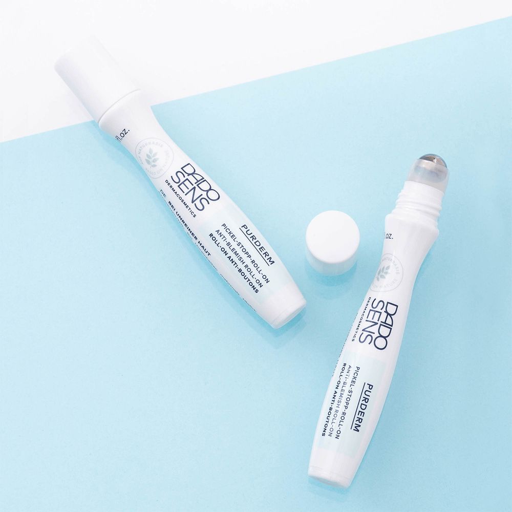 Deux flacons roll-on et un bouchon. Texte: DADO SENS, PURDERM, Roll-on anti-boutons.