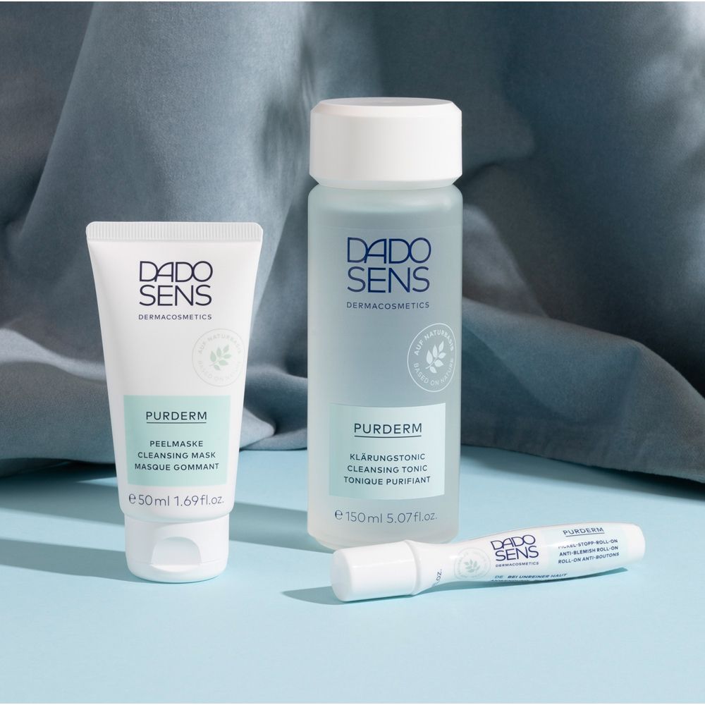 Trois produits DADO SENS PURDERM. Flacon, tube et roll-on. Sur fond bleu.
