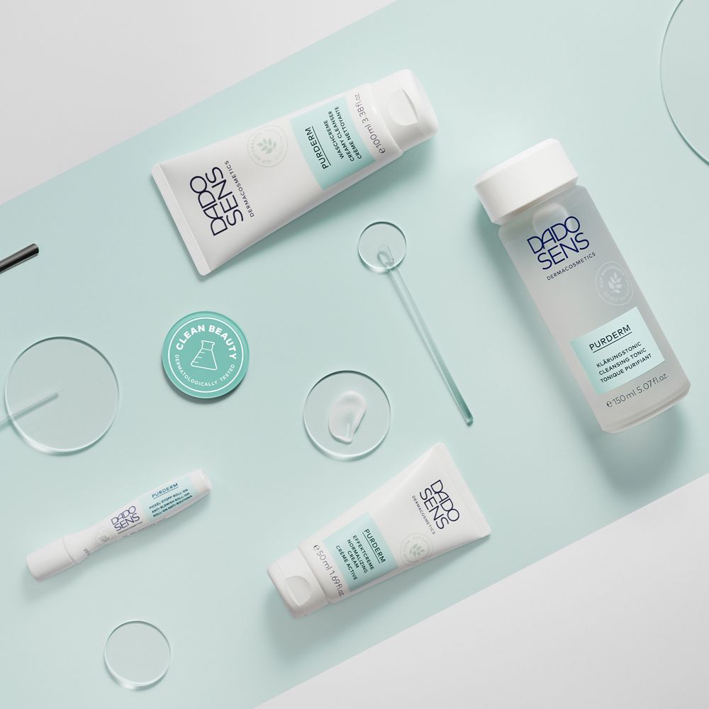 Divers produits DADO SENS PURDERM. Flacons, tubes et accessoires sur fond bleu clair.