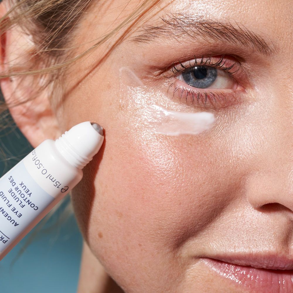 Femme appliquant le fluide contour des yeux. Applicateur roll-on. Peau claire.