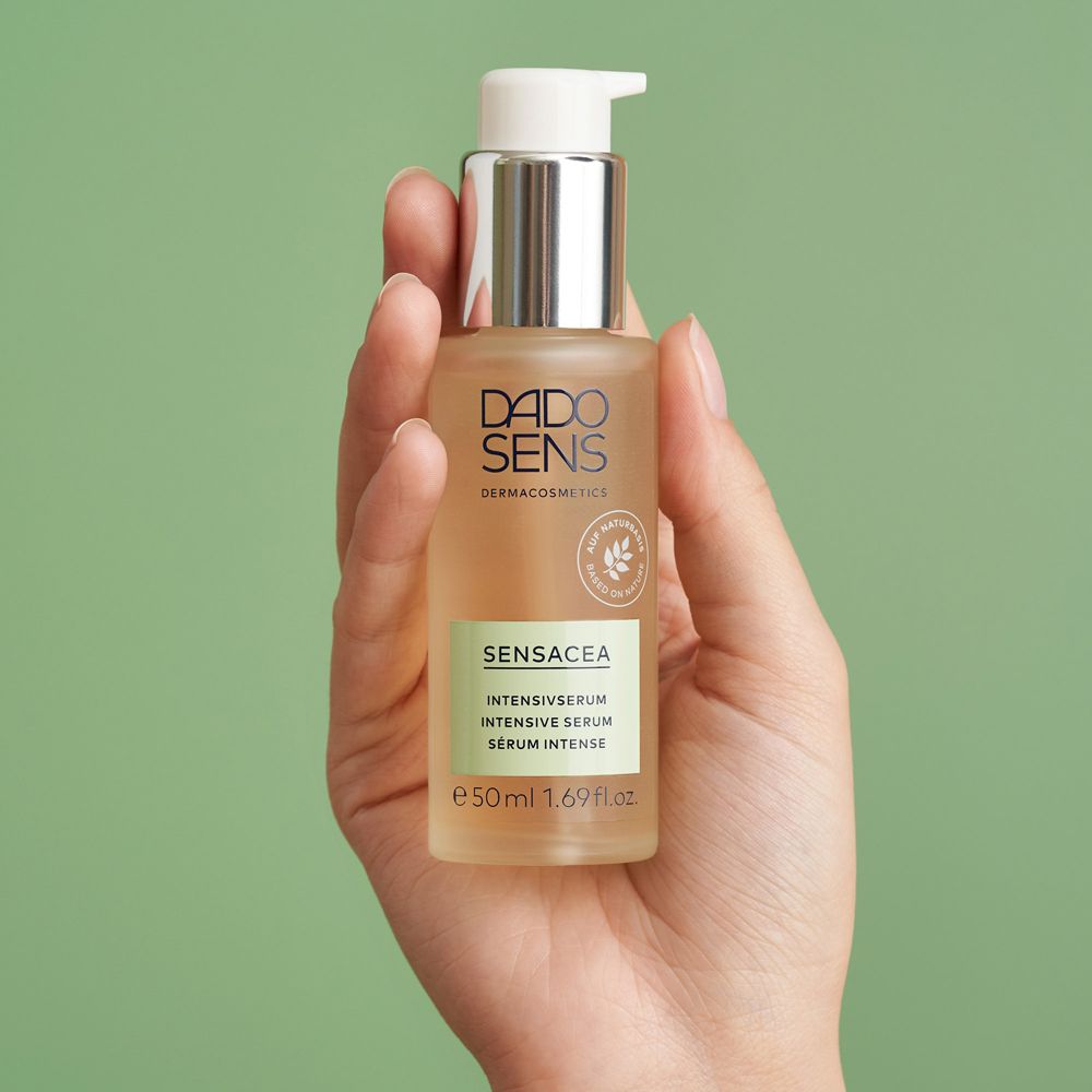 Main tenant flacon DADO SENS SENSACEA Sérum Intensif. Fond vert.