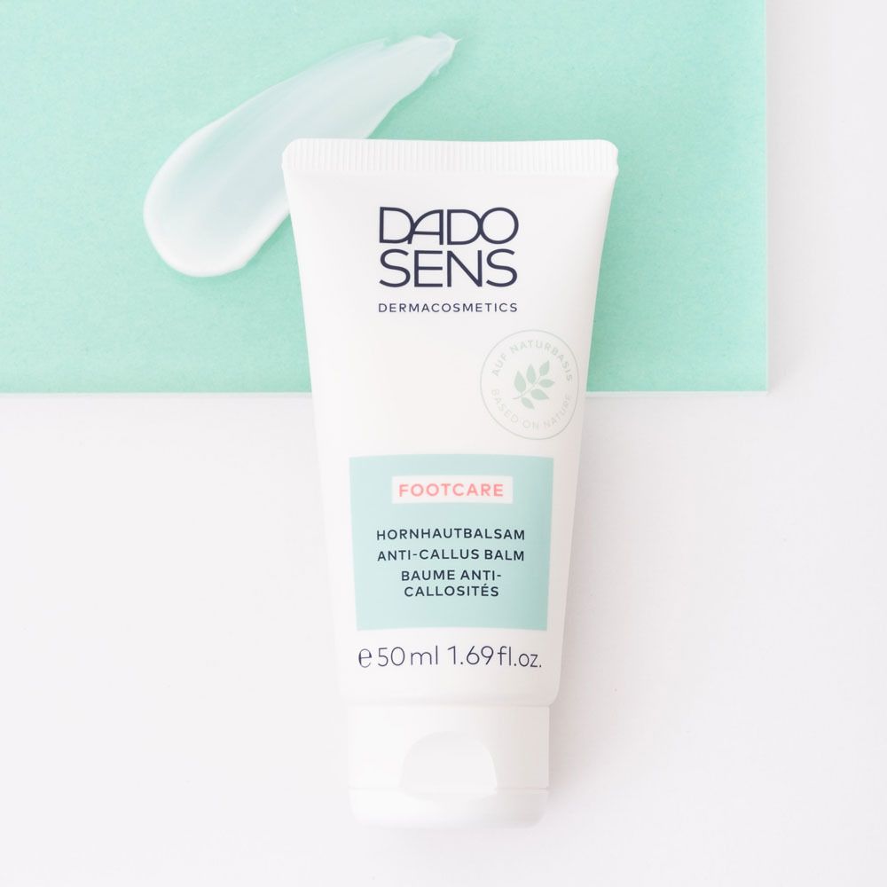 Witte tube met DADO SENS logo en FOOTCARE. Bevat eeltbalsem. Op groene achtergrond.