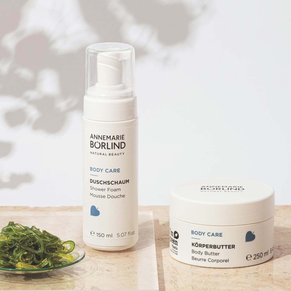 Ensemble de produits blancs. Pot de beurre corporel, flacon de mousse de douche. Verdure.