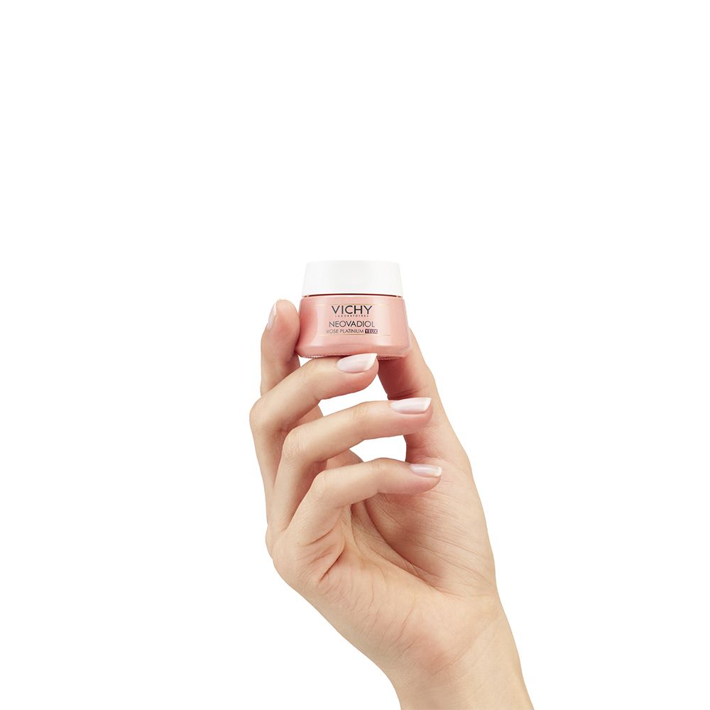 Een hand houdt een kleine pot Vichy Neovadiol Rose Platinium oogverzorging vast.