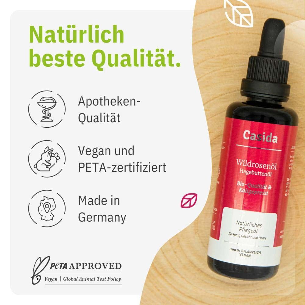 Fles en verpakking. Certificaat 'zeer goed'. Casida Rozenbottelolie. Bio & koudgeperst. Bloemen op de achtergrond.