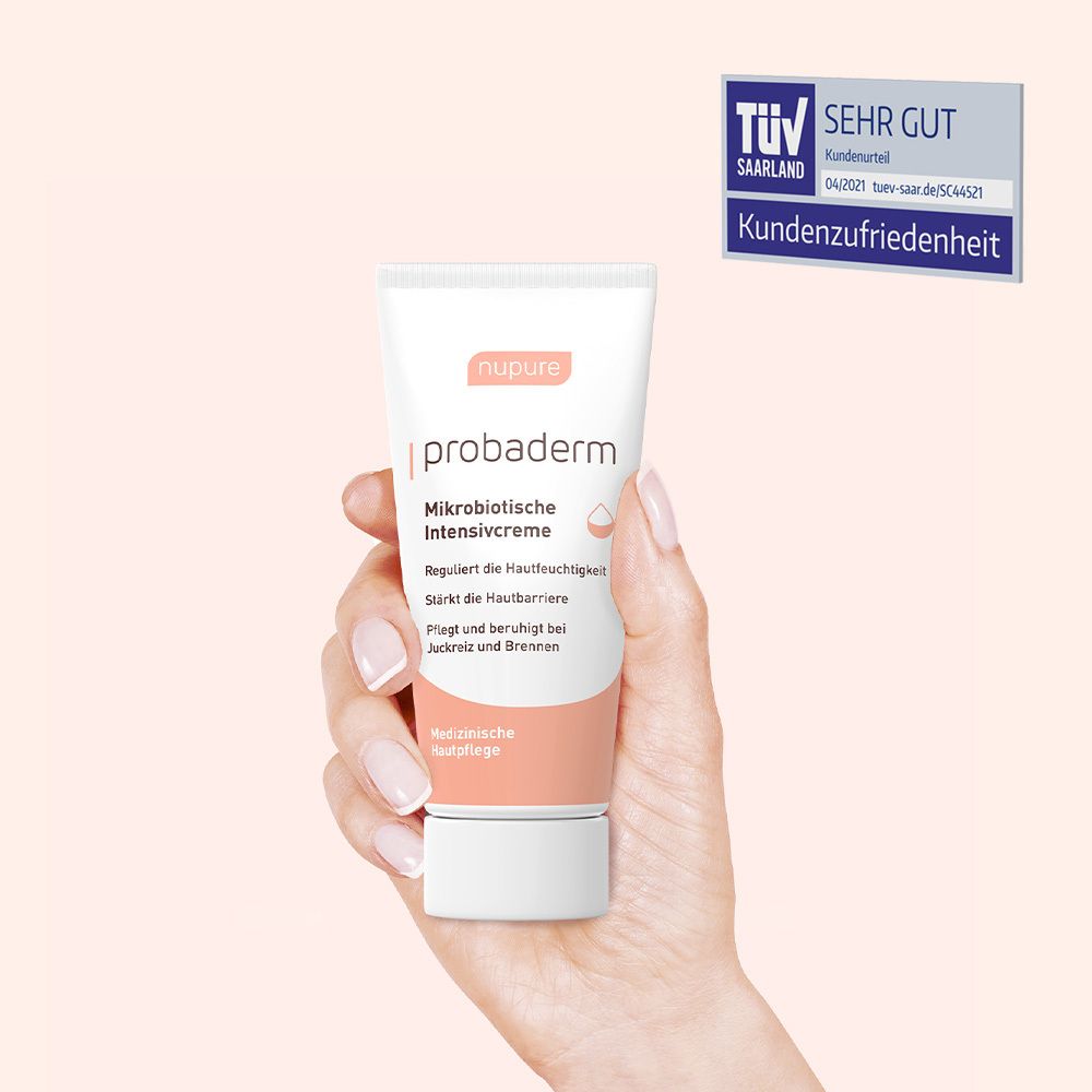 Hand houdt crèmetube vast. Opschrift: nupure probaderm, Microbiotische Intensieve crème. TÜV-keurmerk.