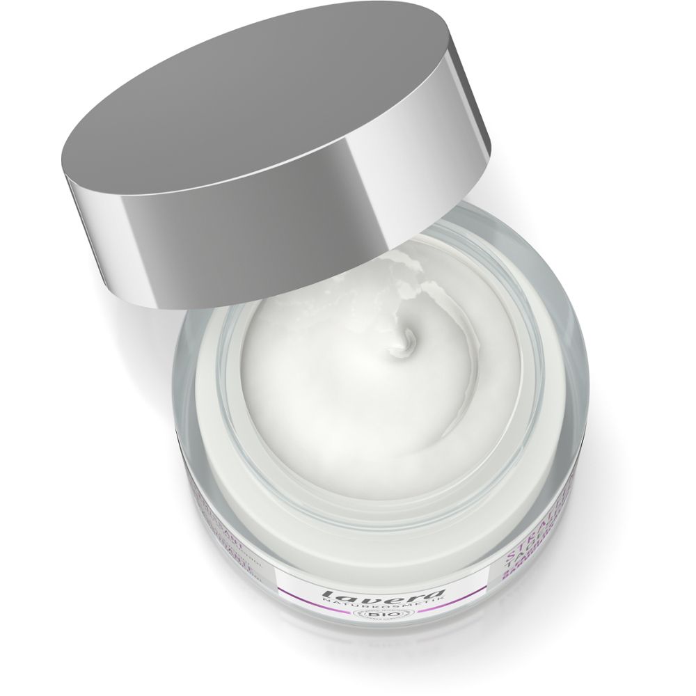 Pot de crème ouvert avec couvercle argenté. Crème blanche visible.