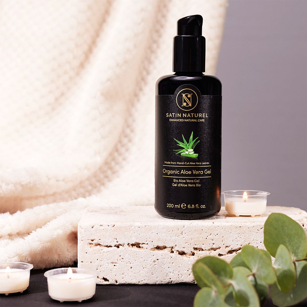 Flacon Gel Bio Aloe Vera SATIN NATUREL sur bloc de pierre avec bougies et eucalyptus.