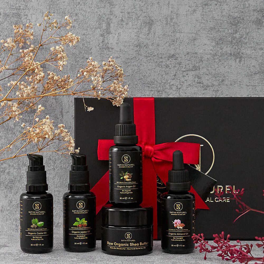 Coffret cadeau avec flacons noirs et pots dans une boîte noire avec ruban rouge. Marque : SATIN NATUREL.