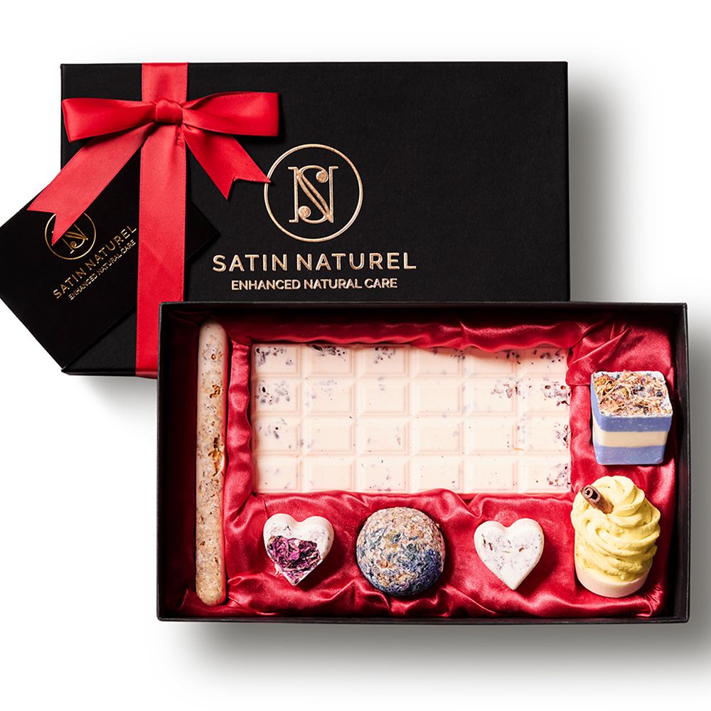 Zwarte geschenkdoos met rode strik. Bevat badpralines in verschillende vormen en kleuren. Logo en tekst op de doos.