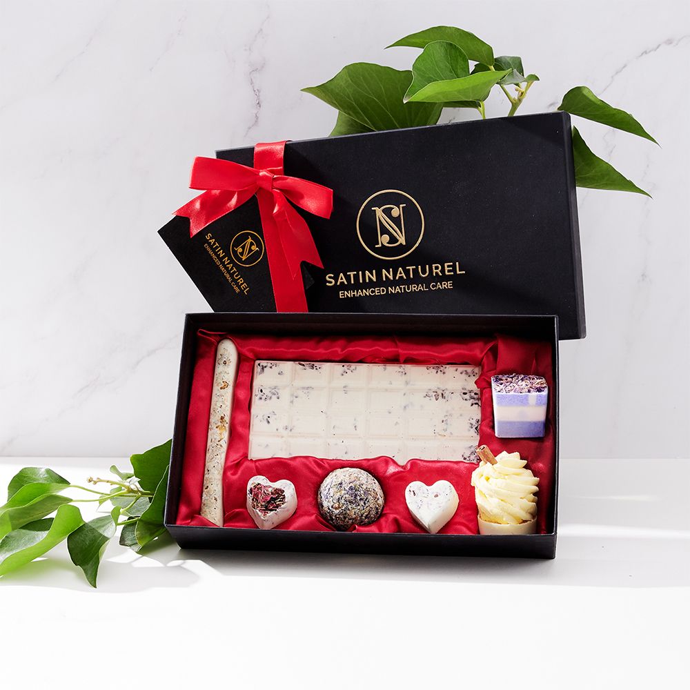 Cadeaudoos met badpralines. Zwarte doos met rode strik. Bevat badpralines in verschillende vormen. Logo en tekst op de doos.