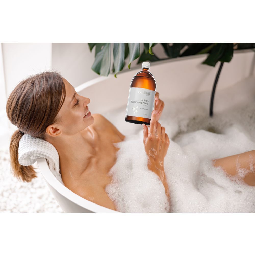 Femme dans une baignoire tenant une bouteille. Flacon en verre brun avec étiquette blanche. Texte: Argent colloïdal ionique 50 PPM, 1000ml.
