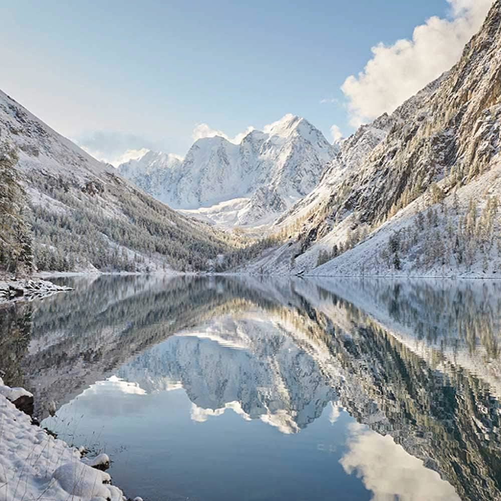 Landschap met besneeuwde bergen, meer en blauwe lucht.
