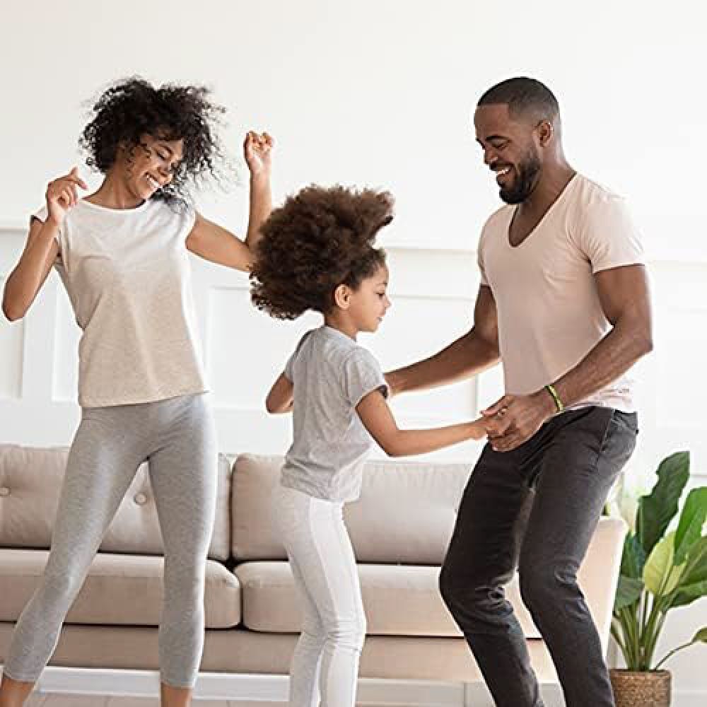 Een gezin danst in de woonkamer. Moeder, vader en dochter bewegen vrolijk.