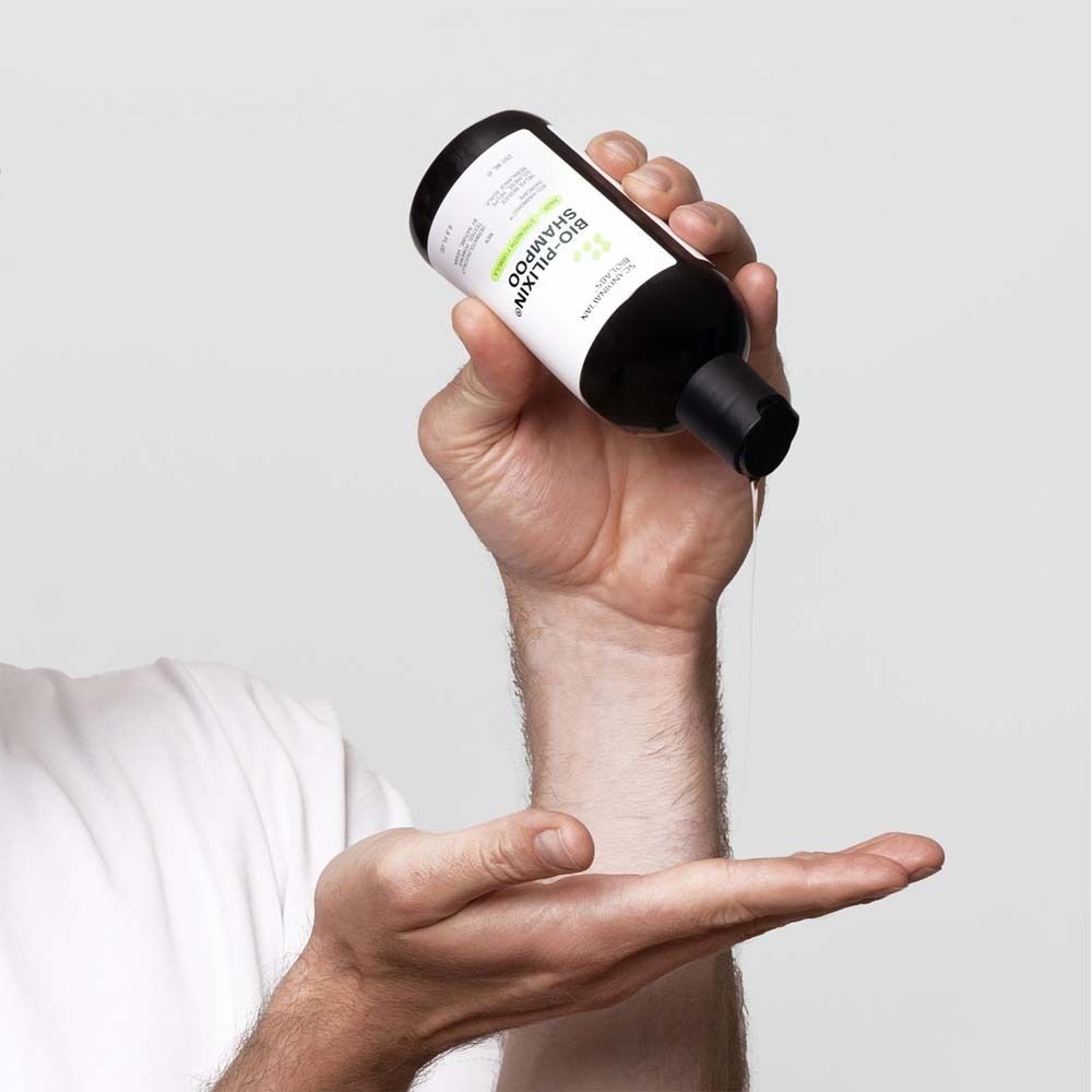 Personne tenant un flacon de shampooing. Inscription : Bio-Pilixin Shampoo.