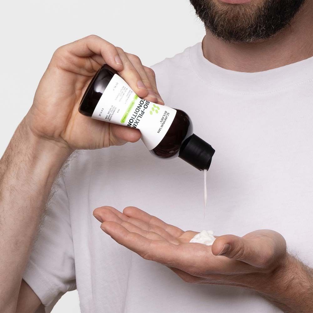 Man giet conditioner in de handpalm. Bruine fles met zwarte dop. Product: BIO-PILIXIN Conditioner.