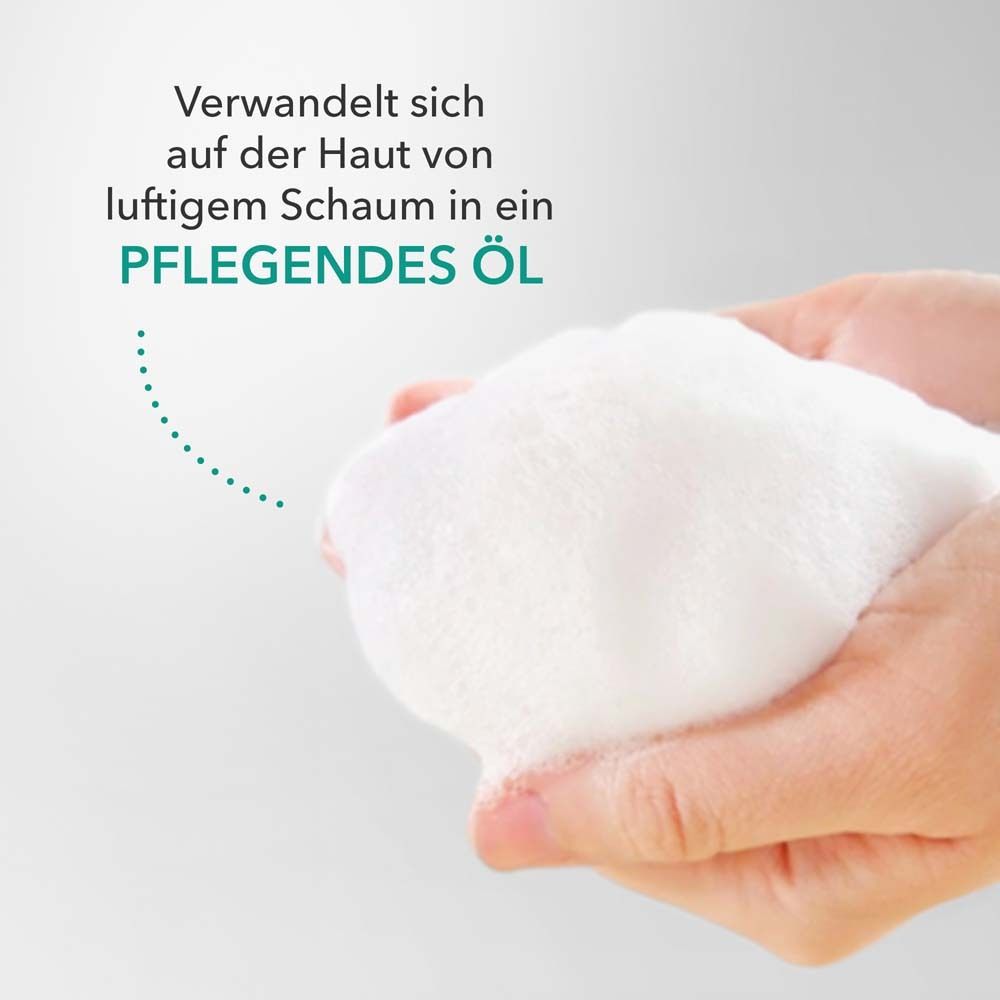 Mains tenant une mousse blanche. Texte : Se transforme sur la peau d'une mousse aérienne en une huile nourrissante.