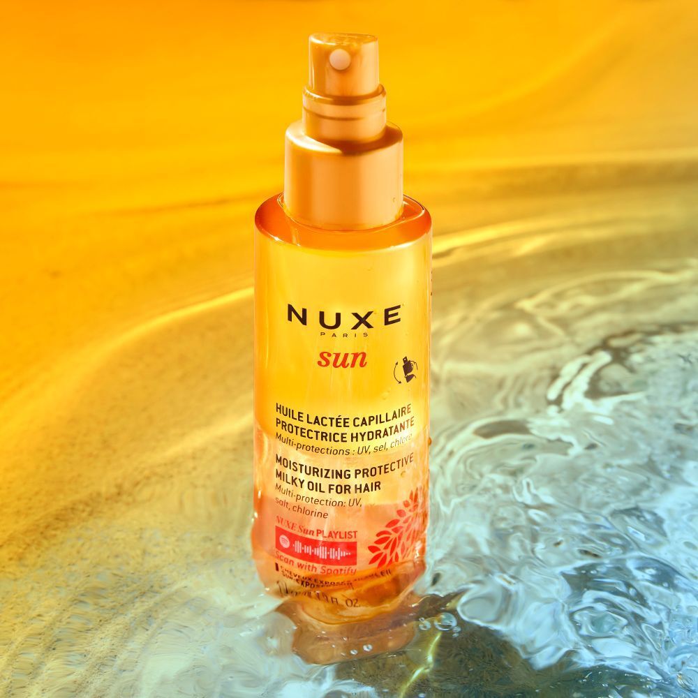 Flacon jaune avec vaporisateur. Texte: NUXE Sun, huile capillaire. Multi-protection: UV, sel, chlore. Dans l'eau.