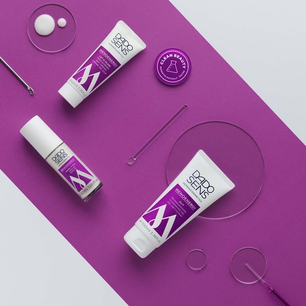 Drie tubes en een potje. Paarse en witte verpakking. Tekst: MENOENERGY. Op paarse achtergrond.