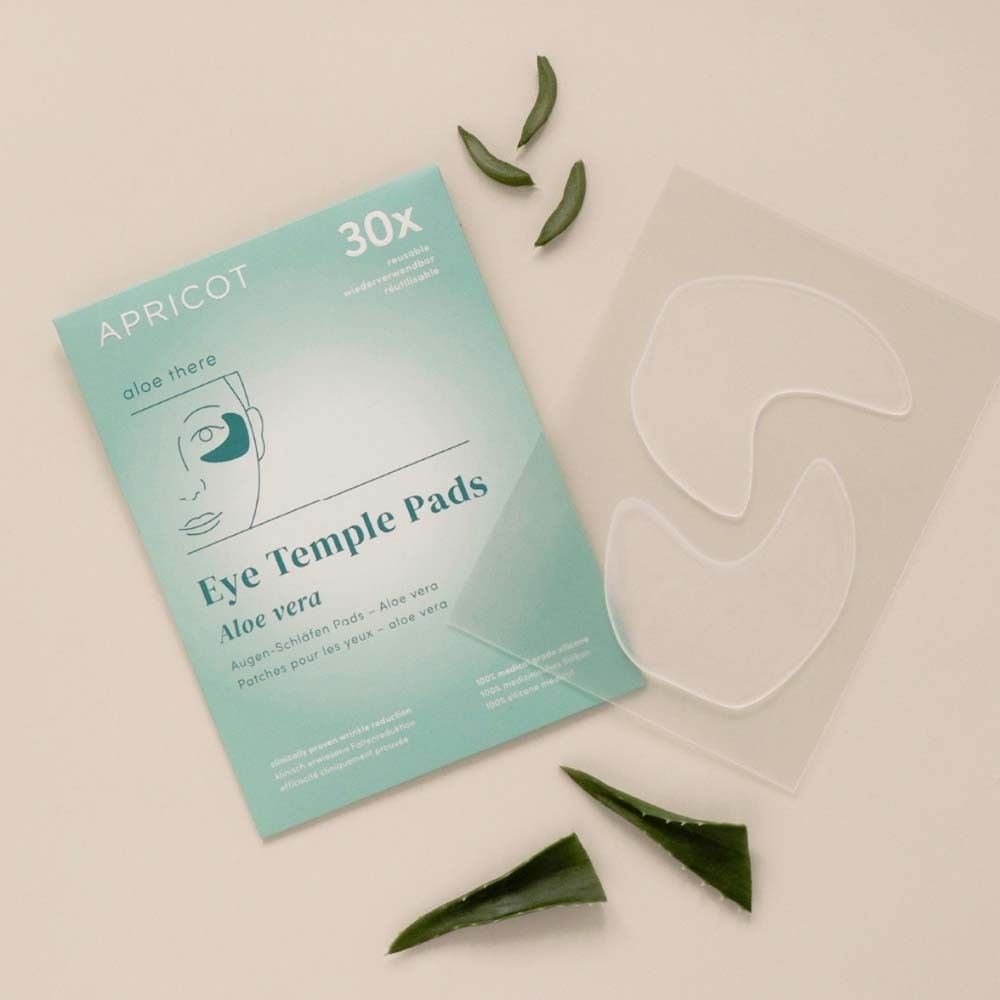 Verpakking en pads van APRICOT Eye Temple Pads. Aloë Vera. Pads en aloë vera bladeren ernaast.