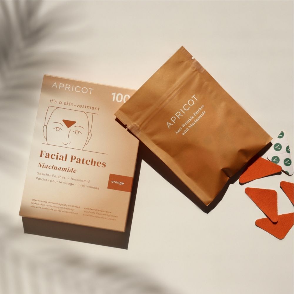 Verpakking en zakje gezichtspatches. Merk APRICOT. Oranje patches. Op lichte achtergrond.