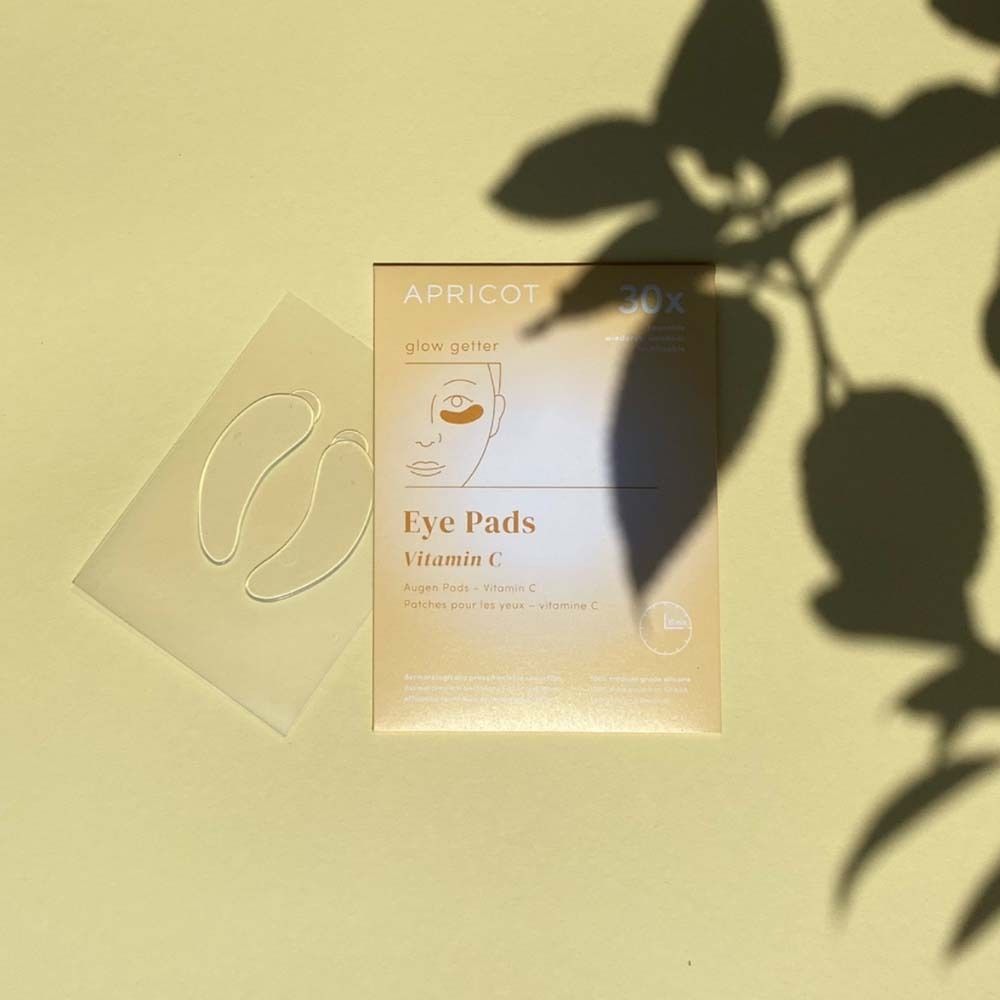 Paquet de coussinets pour les yeux et deux coussinets à côté. Imprimé : APRICOT, Eye Pads Vitamin C.