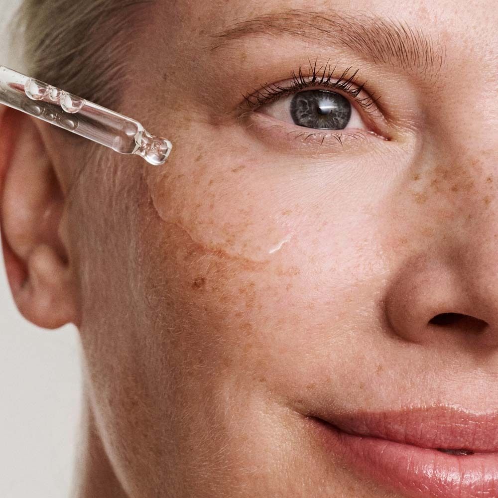 Gros plan : sérum appliqué sur la peau. Pipette. Peau avec des taches de rousseur.