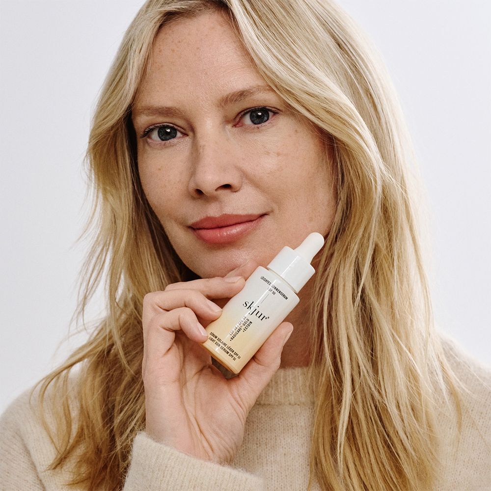 Vrouw houdt skjur lichte zonnecrème SPF 50 flesje vast.