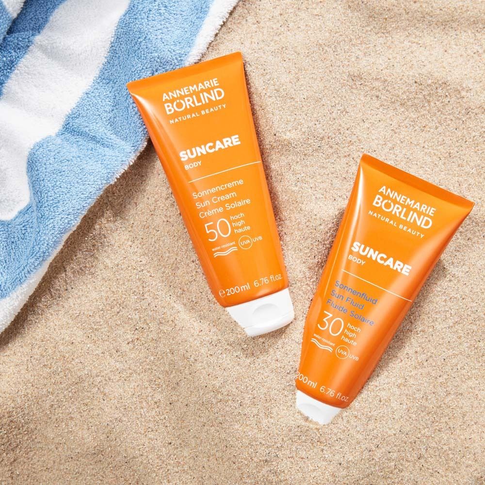 Deux tubes de crème solaire sur le sable. Marque : ANNEMARIE BÖRLIND. SUNCAR Body SPF 50 et 30.