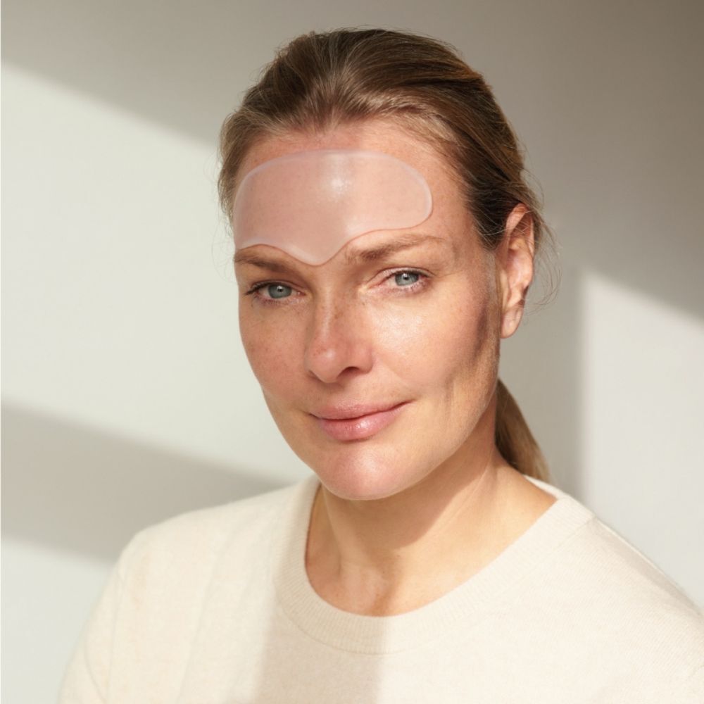 Femme avec un tampon frontal sur le front. Tampon ovale clair. Femme aux cheveux blonds et au teint clair.