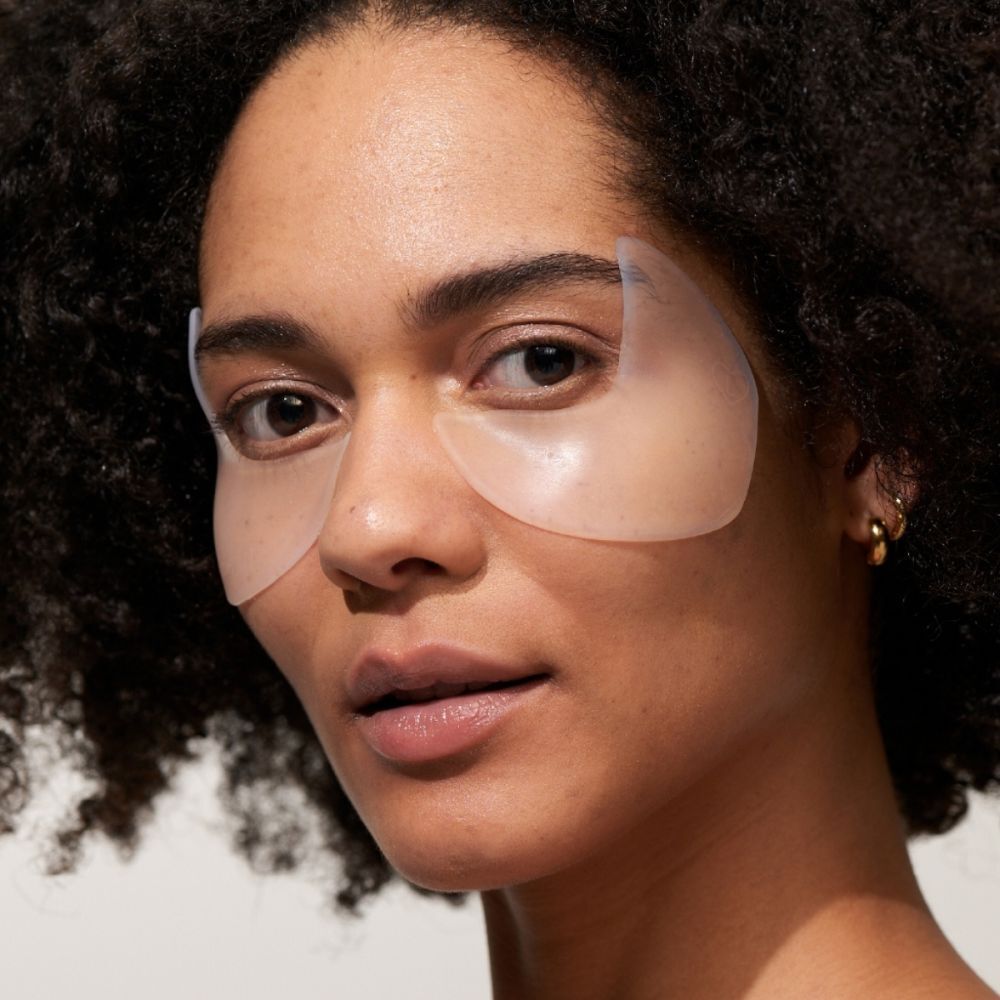 Een vrouw met twee oog-slaap pads op de huid. Pads zijn transparant en bedekken de ogen en slapen.