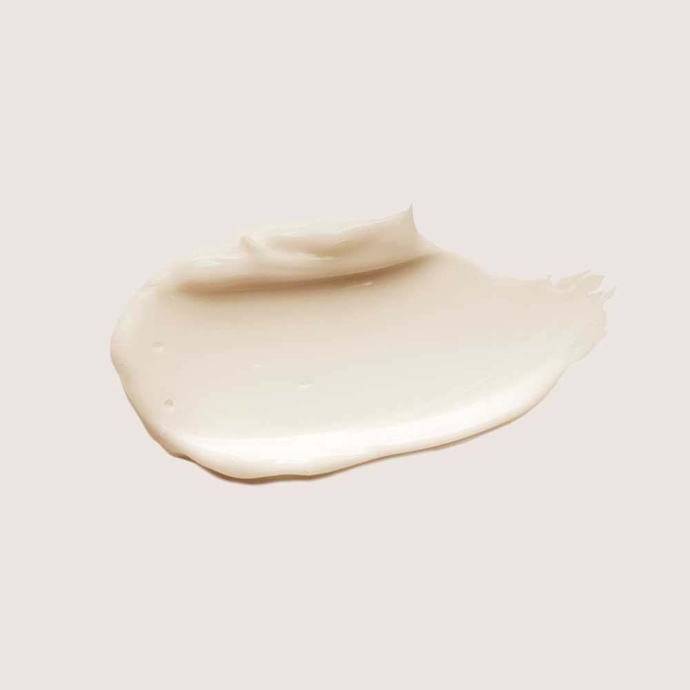 Klodder van een crèmekleurige haarbehandeling op een lichte achtergrond. Gladde textuur.