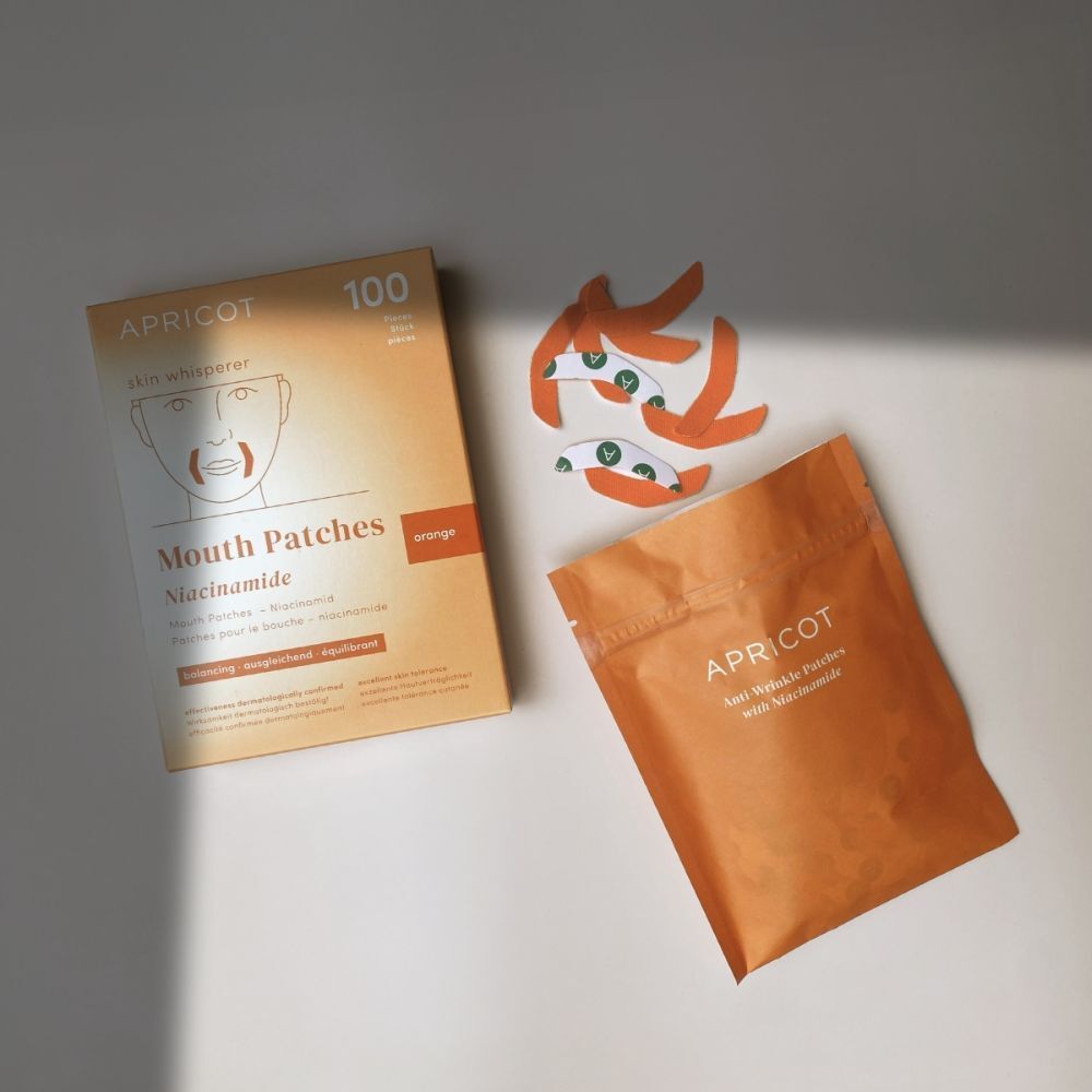 APRICOT Mouth Patches Niacinamide: doos, pouch en verspreide patches op lichte achtergrond.