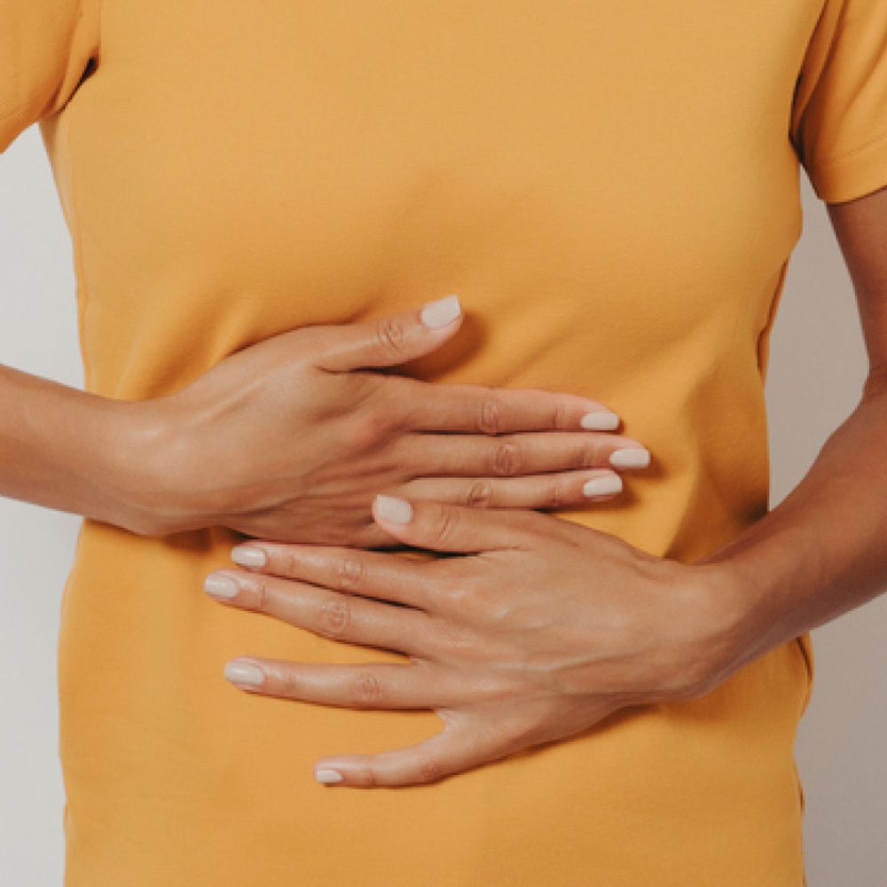 Personne tenant ses mains sur son ventre. T-shirt jaune.