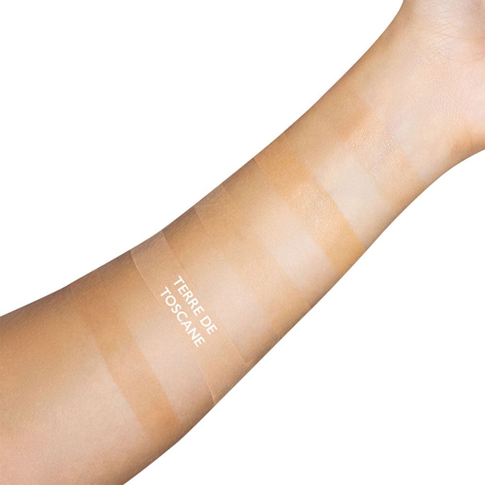 Arm met kleurstalen. Verschillende stroken met verschillende tinten. Tekst: TERRE DE TOSCANE.