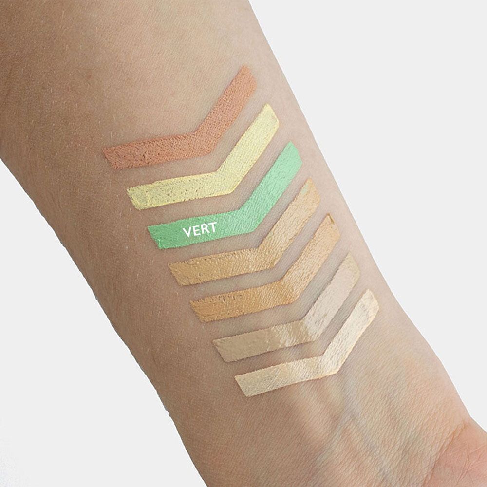 Bras avec échantillons de correcteurs de maquillage. Une nuance verte avec l'inscription VERT.