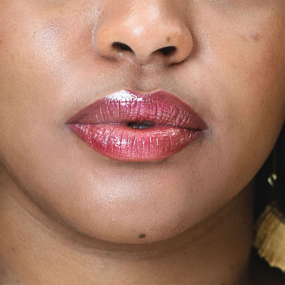 Gros plan sur des lèvres maquillées avec un rouge à lèvres rouge-violet. Les lèvres sont brillantes.