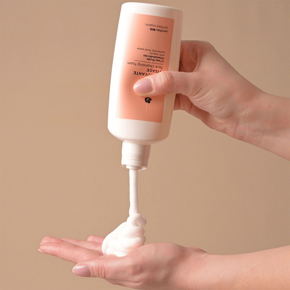 Hand die Avril gezichtsreinigingsschuim uit een fles in de handpalm drukt.