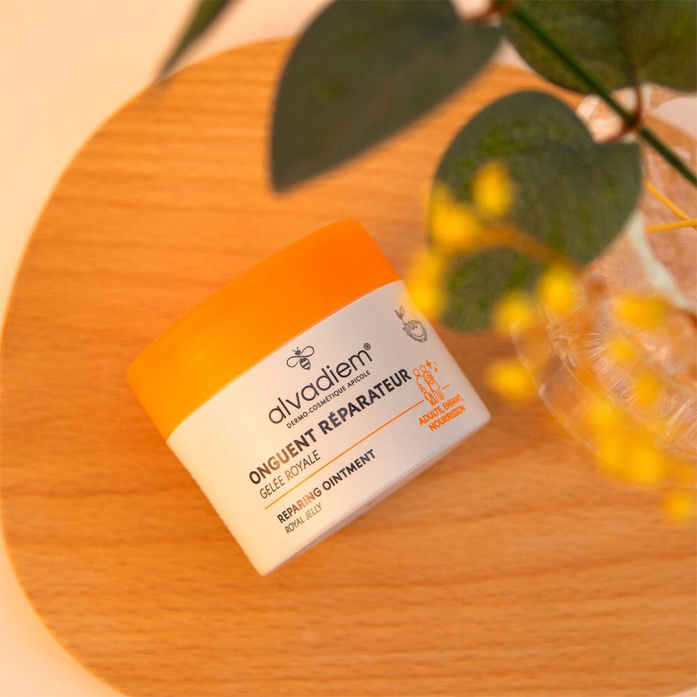 Pot de crème à couvercle jaune sur fond en bois. Inscription: Alvadiem, Onguent Réparateur, Gelée Royale.