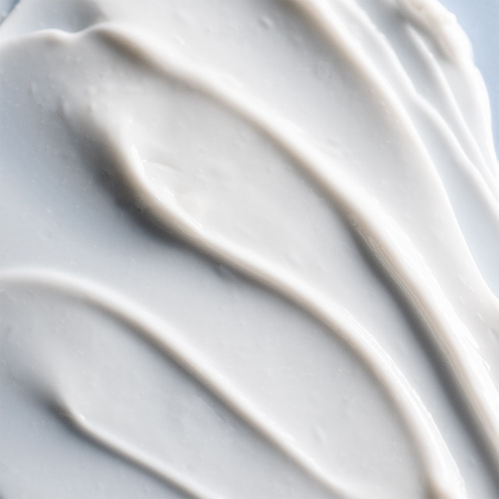 Gros plan de crème blanche. Texture ondulée. Pas d'emballage ni de nom de produit.