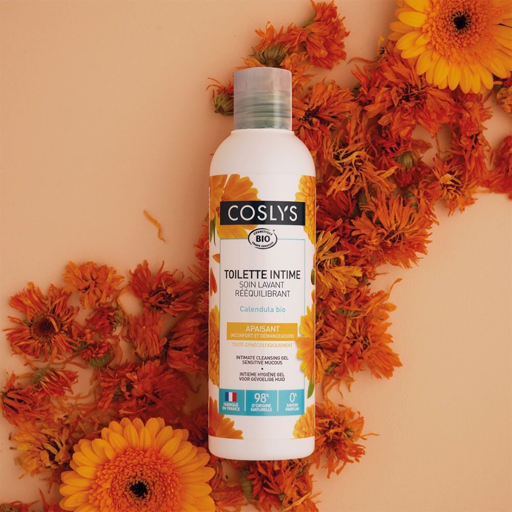 Flacon blanc avec étiquette jaune, entouré de fleurs oranges. Inscription : Coslys, Toilette Intime, Calendula bio.